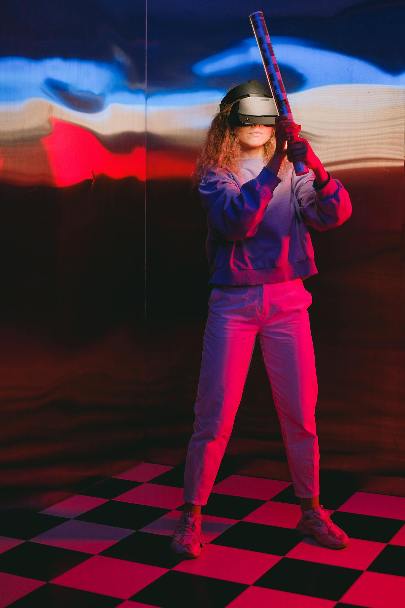 A woman uses a VR headset in a colorful indoor setting with a checkered floor.