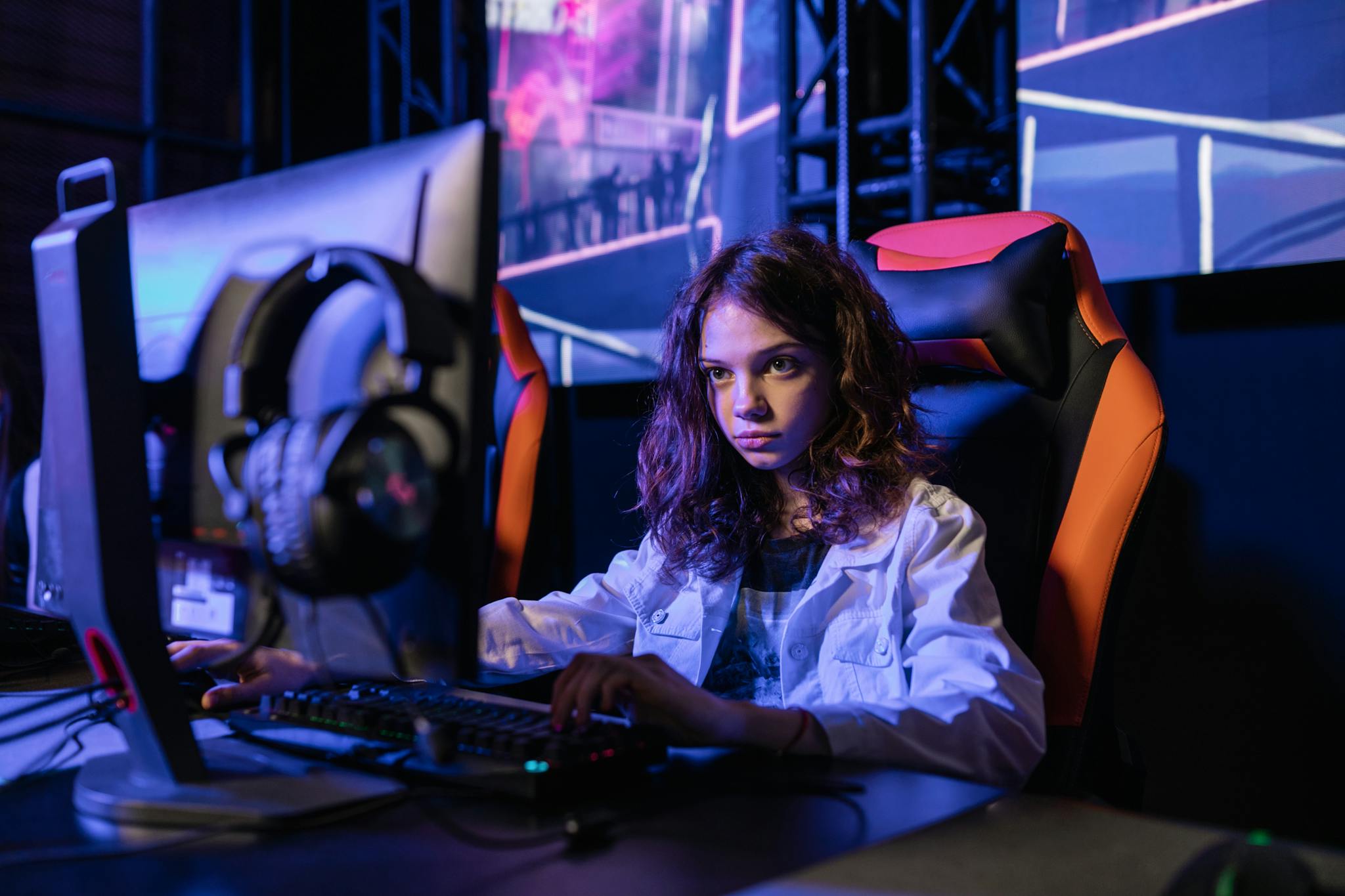 A young woman intensely playing video games in a gaming chair, indoors.